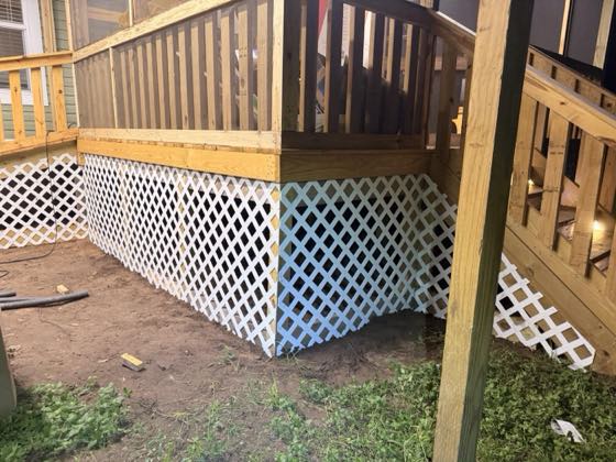 White lattice skirting fitted beneath a wooden deck and stair.