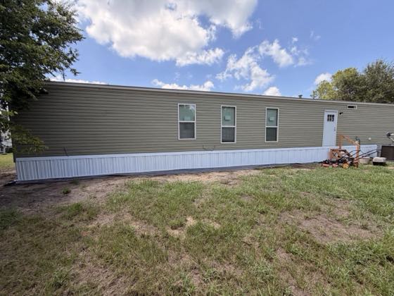A long sage green home photographed broadside, white skirting running end to end.