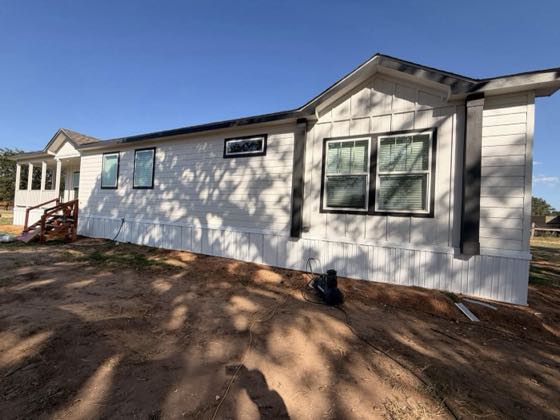 A white board-and-batten home with black-trimmed windows and new white skirting.