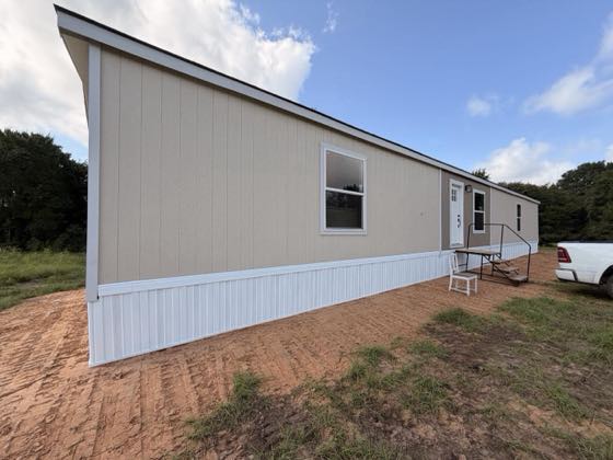 A tan home seen down its long side, white skirting drawing a straight line to the corner.
