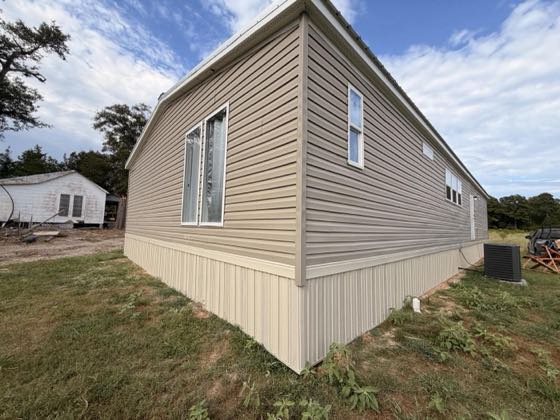 The corner of a cream home with cream skirting meeting the grade.