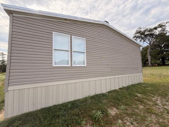 The gable end of a tan home with tan skirting following the ground.