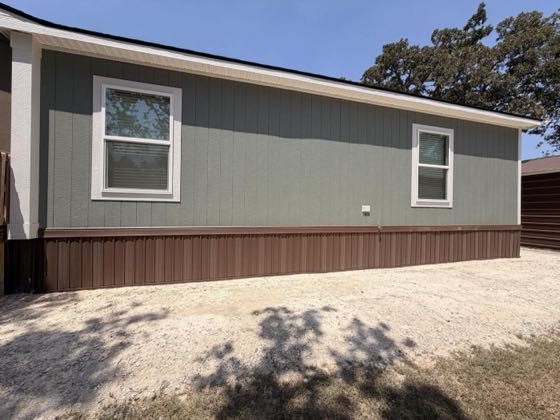 A sage green home photographed broadside with brown skirting end to end.